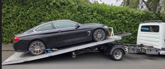 A black Bentley car is taken on a recovery truck